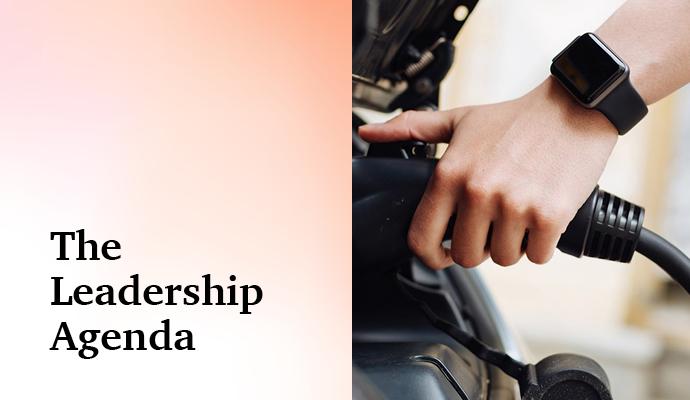 Person wearing a smartwatch connecting a charging plug to an electric car with the words "The Leadership Agenda" superimposed Person wearing a smartwatch connecting a charging plug to an electric car with the words "The Leadership Agenda" superimposed