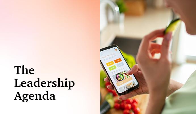 Photograph of a person's hand holding a phone while eating with the words "The Leadership Agenda" superimposed Photograph of a person's hand holding a phone while eating with the words "The Leadership Agenda" superimposed