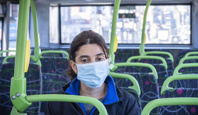 A woman in a surgical mask riding a city bus A woman in a surgical mask riding a city bus
