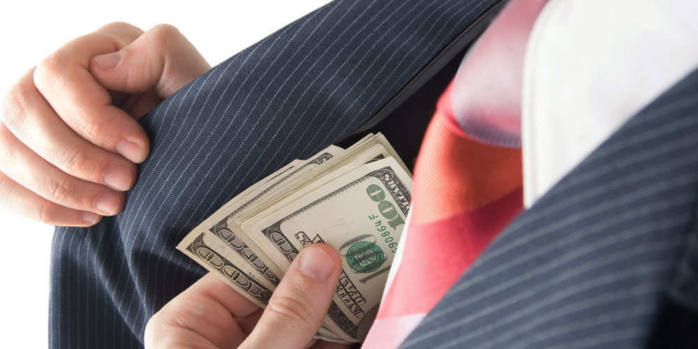 A man dressed in a pinstripe suit furtively pockets $100 bills. A man dressed in a pinstripe suit furtively pockets $100 bills.