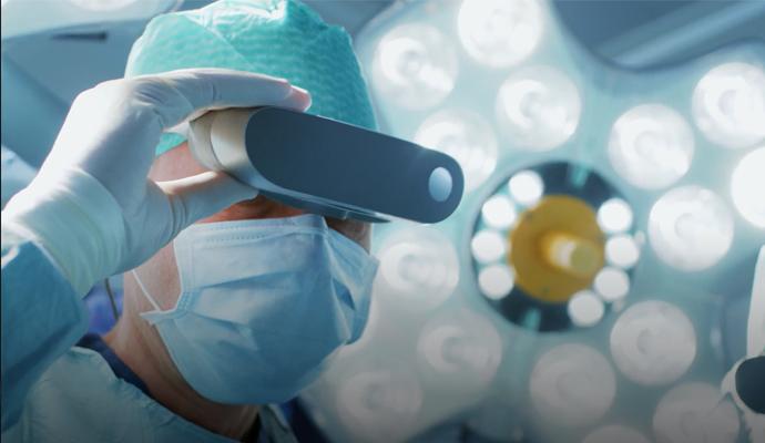 Surgeon wearing protective gear and examining through a handheld medical device Surgeon wearing protective gear and examining through a handheld medical device