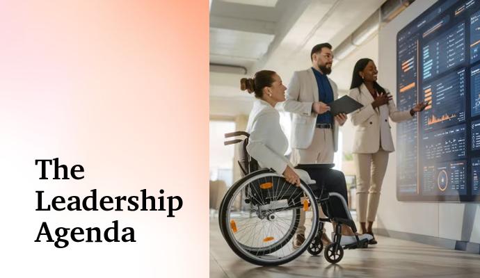 Team of colleagues standing and seated in a wheelchair, discussing charts displayed on a wall monitor. Team of colleagues standing and seated in a wheelchair, discussing charts displayed on a wall monitor.