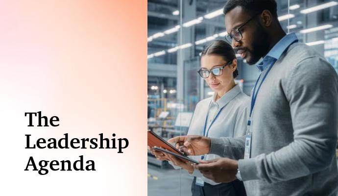 Two professionals standing in an industrial workspace, looking at a tablet together. Two professionals standing in an industrial workspace, looking at a tablet together.